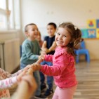 Happy group of kids playing a game of tug of war in playroom