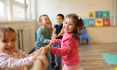 Happy group of kids playing a game of tug of war in playroom