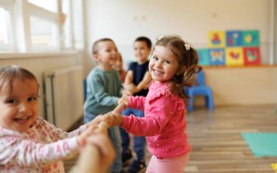 Happy group of kids playing a game of tug of war in playroom