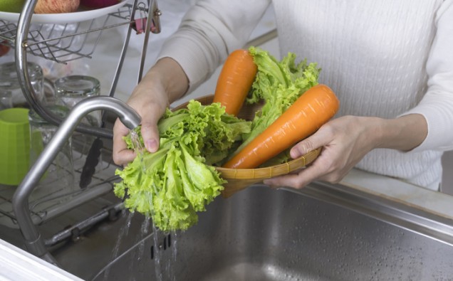 woman hand washing organic lettuce and carrots vegetables in the kitchen