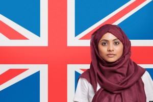 Portrait of young Muslim woman in traditional clothing standing against British flag