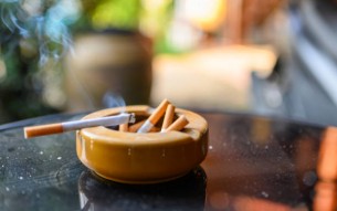 Cigarette burning with smoking on ceramic ashtray