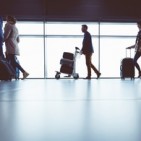 Silhouette of people walking with luggage in airport terminal