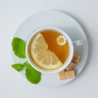 top-view-cup-chamomile-tea-with-lemon-mint-leaves-sugar-white-surface-horizontal_176474-5080
